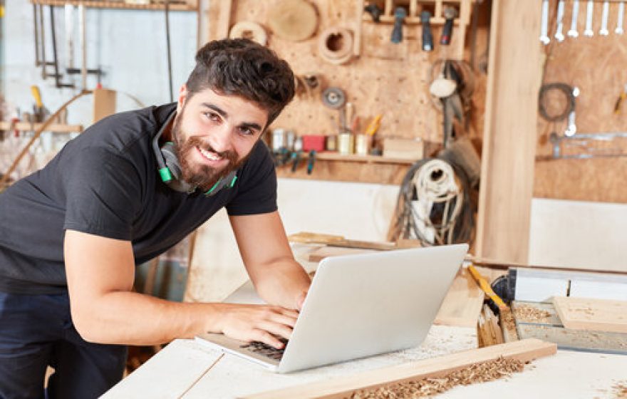 Young man at online customer service at laptop. Computer in his joinery